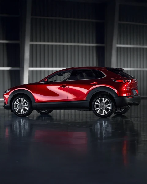 Mazda CX-30 en rojo Soul Red Crystal vista lateral en entorno industrial, crossover deportivo y elegante.